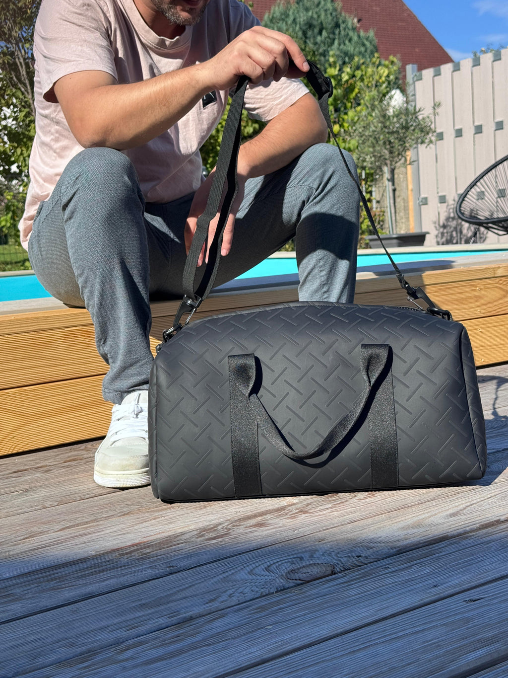 LS Fashion black weekender bag with quilted pattern placed on wooden deck outdoors