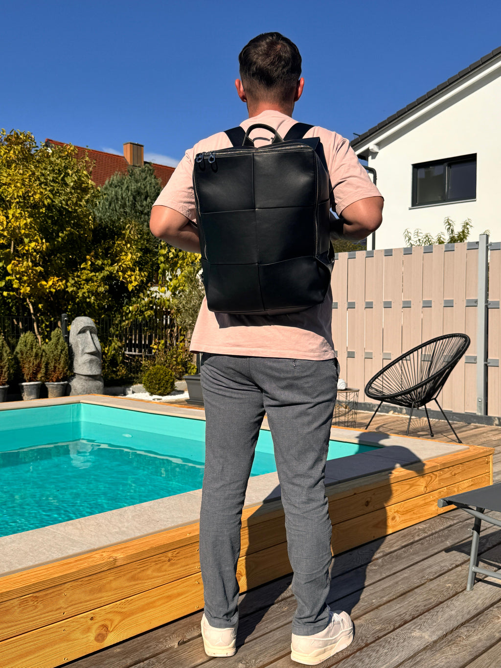 Man wearing LS Fashion black leather rucksack standing by a pool in casual outfit